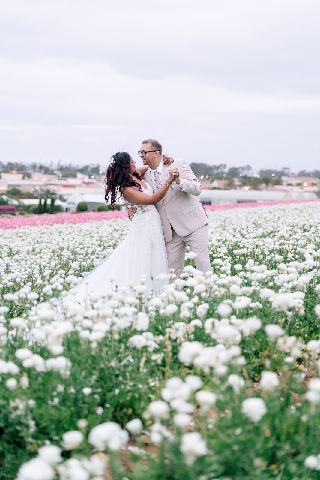 Bride and groom dancing in a field of white ranunculus